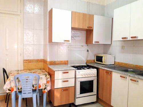 a small kitchen with white cabinets and a table and chairs at Residence Ahlem in El Aouina