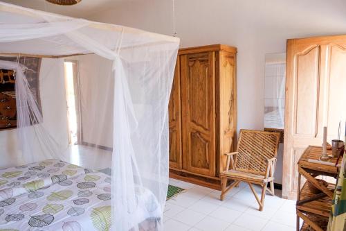 a bedroom with a bed with a mosquito net at Keur Dofie in Toubab Dialaw