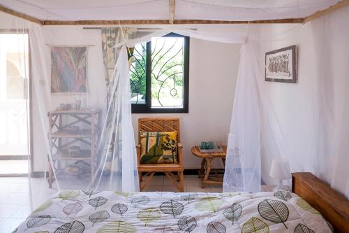 a bedroom with a bed with a canopy and a window at Keur Dofie in Toubab Dialaw