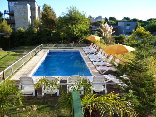une piscine avec chaises longues et parasols dans l'établissement Terra Magna, à Mar de las Pampas