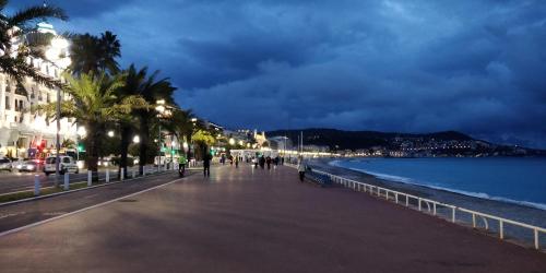 a city street with palm trees and the ocean at night at Nice Seaview Free Parking 4.Pers in Nice