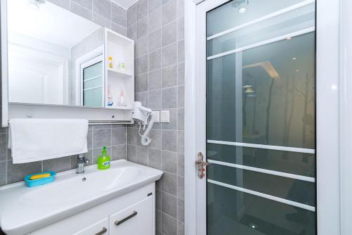 baño con lavabo y puerta de ducha acristalada en Henan Luoyang·Luo River· Locals Apartment 00137320 en Luoyang