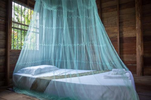 a bed with a mosquito net in a room at Chansor Community Homestay 6 in Phumĭ Trach Pôk (2)