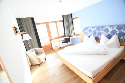 a bedroom with a bed and a chair and a window at Hotel Ucliva in Waltensburg