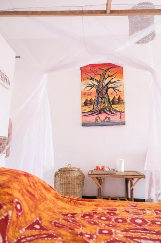 a bedroom with a bed and a table with a tree at Keur Dofie in Toubab Dialaw