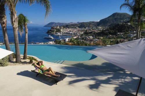 a woman sitting on a beach chair next to a swimming pool at Hotel Villa Enrica - Aeolian Charme in Lipari