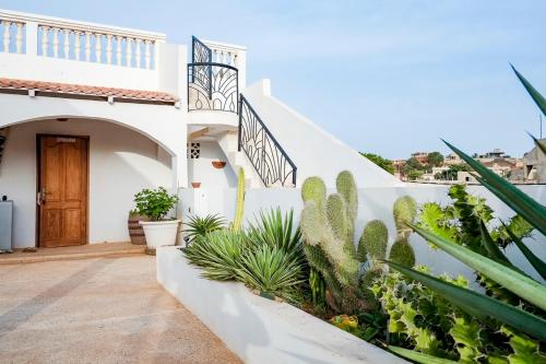 a white house with a staircase and cactus at Keur Dofie in Toubab Dialaw