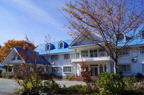a large white house with a blue roof at Pension Bloom in Gujo