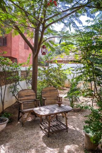 a picnic table and two chairs under a tree at Keur Dofie in Toubab Dialaw