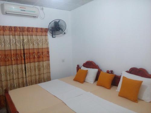 een slaapkamer met een bed met oranje kussens en een ventilator bij Pelwehera Homestay in Dambulla