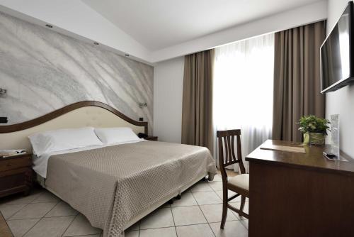 a hotel room with a bed and a desk and a television at Hotel Nicoletta in Santa Maria Navarrese