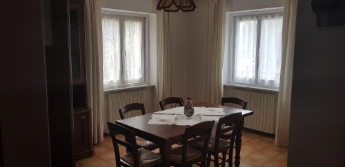 een eetkamer met een tafel, stoelen en ramen bij Casa vacanze in Trentino. Altopiano di Lavarone in Lavarone