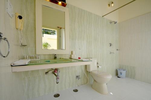 uma casa de banho com um lavatório, um WC e um espelho. em Aaram Baagh Pushkar by Pachar Group em Pushkar