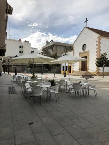 eine Terrasse mit Tischen, Stühlen und Sonnenschirmen in der Unterkunft Pensión Juan Pedro in Roquetas de Mar