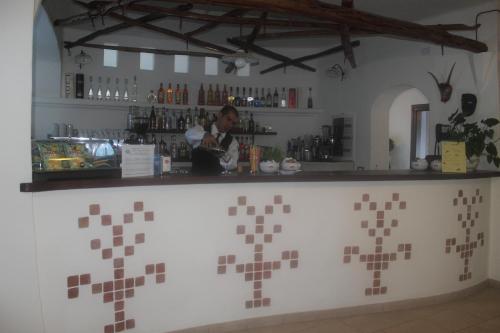 a woman standing behind a counter in a bar at Hotel Resort Nuraghe Arvu in Cala Gonone