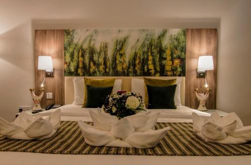 1 dormitorio con 1 cama grande y una pintura grande en Royal View Hotel, en Ras al Khaimah