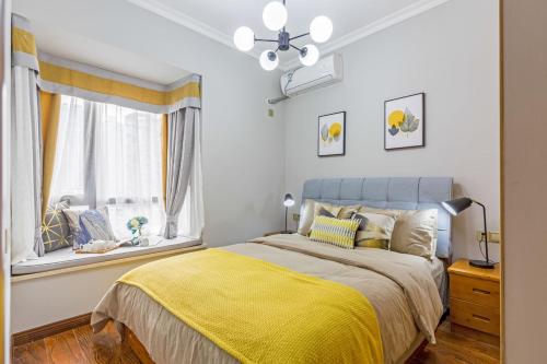 a bedroom with a bed with a yellow blanket and a window at Chongqing Yubei·Chongqing North Railway Station· Locals Apartment 00138340 in Chongqing