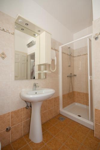 a bathroom with a sink and a shower with a mirror at Apartments Valentino in Vrsar