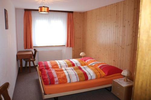 a bedroom with a bed with a colorful quilt on it at Haus Amara in Saas-Grund