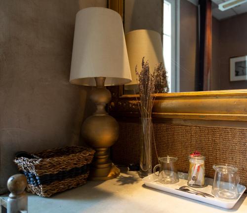 une lampe sur une table dans une pièce avec un miroir dans l'établissement Hotel Mignon, à Avignon