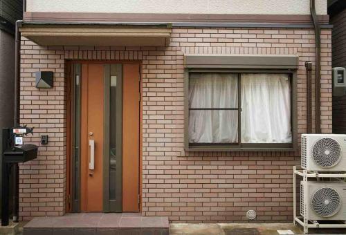 a brick house with a door and a window at Maguro House in Osaka