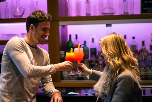 a man and a woman holding a drink in a bar at Mercure Curitiba Batel in Curitiba