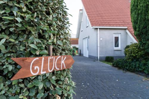 a sign on the side of a bush with a house at Aloha Beach House in Scharendijke