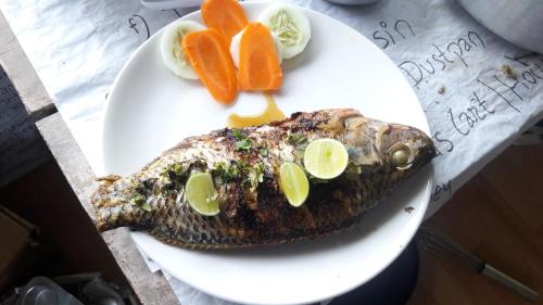 a plate of food with a fish and oranges at Begnas Coffee House & Hotel in Deorāli