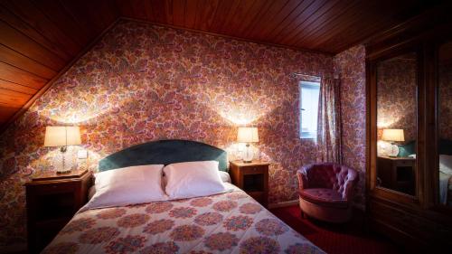 a bedroom with a bed and two lamps and a chair at Hôtel des Deux Clefs in Turckheim