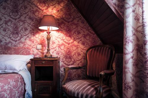 a bedroom with a bed and a lamp and a chair at Hôtel des Deux Clefs in Turckheim