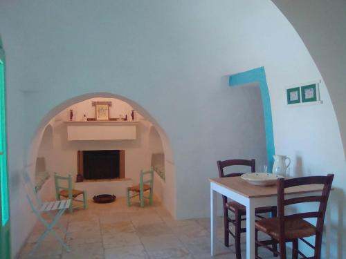 a room with a table and chairs and a fireplace at Il Trullo del Nonno a Cisternino in Cisternino