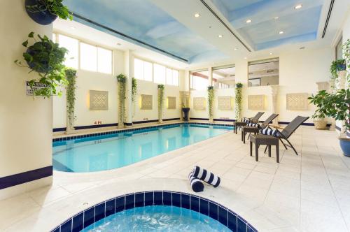 a pool with tables and chairs in a large room at Al Safir Tower - Residence in Juffair