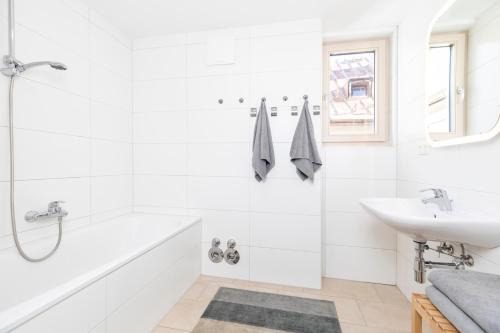 a white bathroom with a sink and a bath tub at Top of Innsbruck in Innsbruck