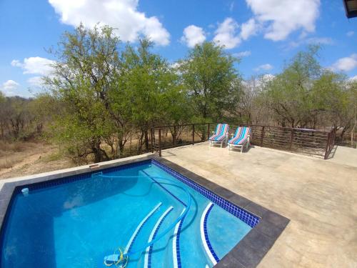 a swimming pool on a patio with two chairs at Lionsview Private Lodge - 6 Lions in Marloth Park