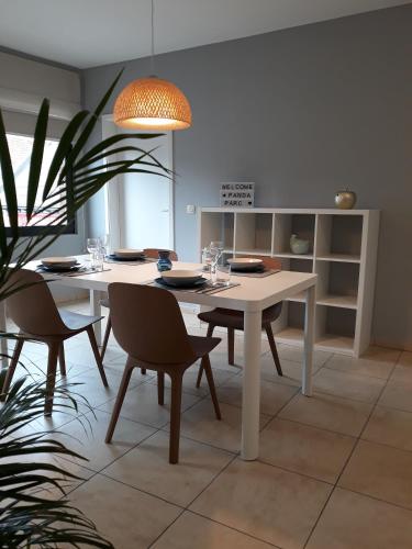 une salle à manger avec une table et des chaises blanches dans l'établissement Panda Parc Appartment proche Pairi Daiza-Shape-Nato, à Lens