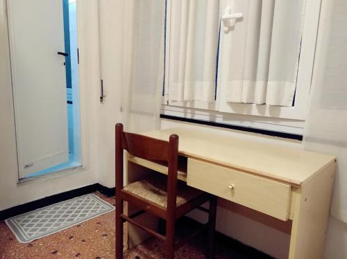 un bureau en bois avec une chaise à côté d'une fenêtre dans l'établissement Hotel Suisse, à Sestri Levante