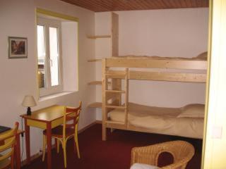 a bedroom with a bunk bed and a table and a desk at Hôtel du Centre in Villard-de-Lans