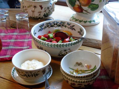 a wooden table with bowls of fruit and whipped cream at Pwllgwilym B & B in Builth Wells
