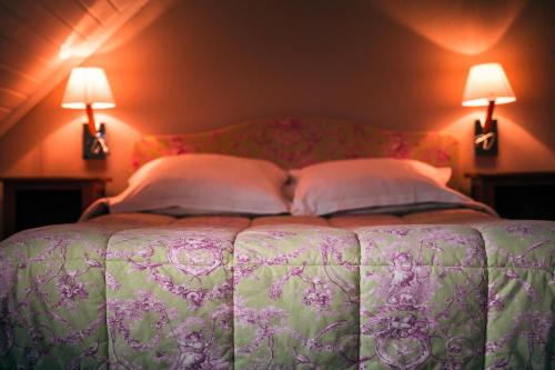 a bed in a room with two lamps on the wall at Hôtel des Deux Clefs in Turckheim