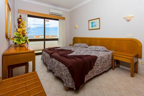 un dormitorio con una cama y una ventana en Aparthotel Paladim & Alagoamar, en Albufeira