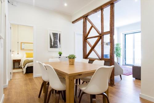 a dining room with a wooden table and white chairs at Central Downtown by Central Hill Apartments in Lisbon