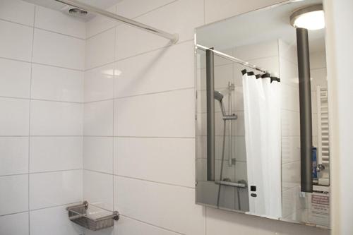 a white bathroom with a shower and a mirror at Velvetamsterdam in Amsterdam