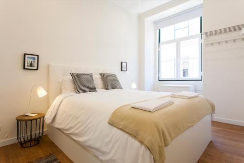 a white bedroom with a large bed with a window at Central Downtown by Central Hill Apartments in Lisbon