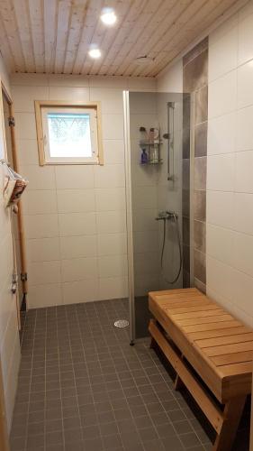 uma casa de banho com um chuveiro com um banco em Aurinkolinna 12 em Peräseinäjoki