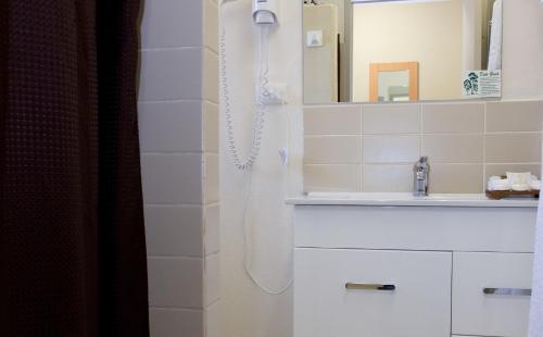 a white bathroom with a shower and a sink at Hideaway Motor Inn in Armidale