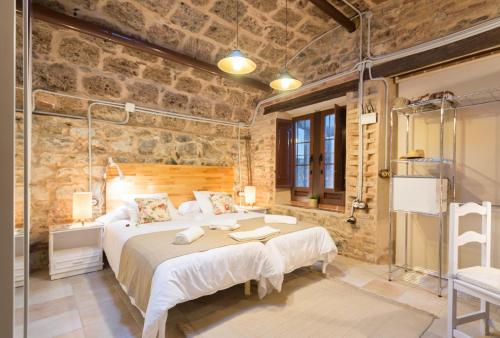 1 dormitorio con 1 cama grande y pared de piedra en Villa Amalia Suites Malaga, en Málaga