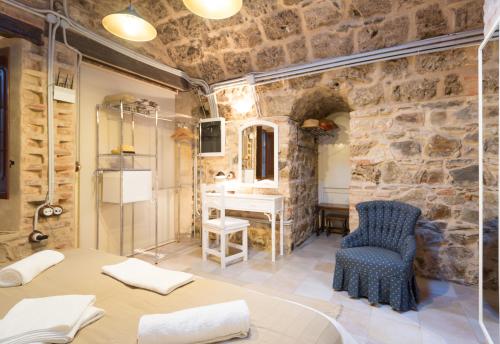 Baño con paredes de piedra, mesa y silla en Villa Amalia Suites Malaga, en Málaga