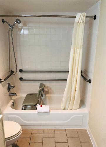 a bathroom with a bathtub with a chair in it at Super 8 by Wyndham Gulfport Airport NW Near Biloxi in Gulfport