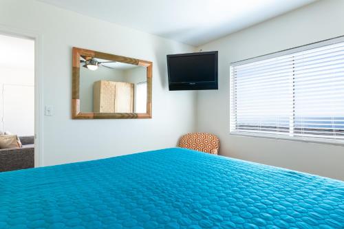 a bedroom with a blue bed and a mirror at The Sea View Inn At The Beach in Manhattan Beach