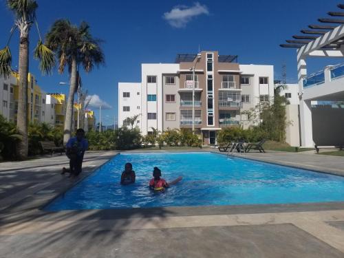 two children swimming in a swimming pool in a apartment at Oasis Palma Real santiago, Republica Dominicana in Santiago de los Caballeros